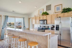 a kitchen with a counter with stools and a refrigerator at Seaside 46 in Nags Head