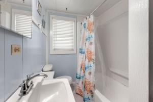 a bathroom with a sink and a toilet and a shower curtain at Seasons in the Sun in Nags Head +20 photos
