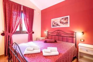 een rode slaapkamer met een bed met twee witte handdoeken bij Villa Torre del Mare in Scopello