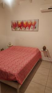 a bedroom with a red bed and a painting on the wall at Villa Bellevue in Sainte-Rose