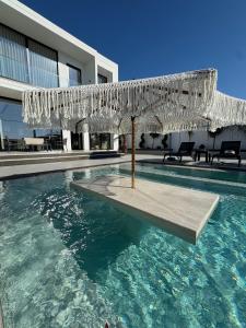 a swimming pool with an umbrella in the water at Soléa Villa in Rrushkull