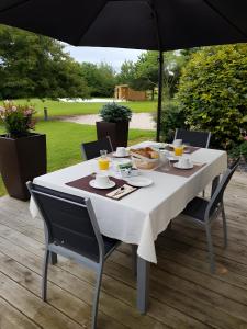 a white table with chairs and an umbrella at La Ferme Aux Arts in Beaumont-sur-Grosne