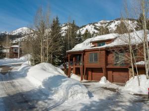 a log cabin in the snow with trees and mountains at RMR: Moose Creek 17 Condo in Teton Village in Teton Village