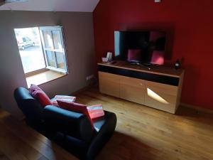 a living room with a couch and a tv at La Ferme Aux Arts in Beaumont-sur-Grosne