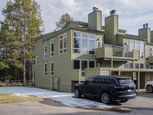 Una camioneta negra estacionada frente a una casa verde. en RMR: Windflower 2121 Condo in The AspensWilsonWY, en Wilson
