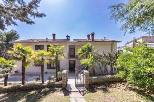 ein großes Haus mit Palmen davor in der Unterkunft Apartment Rabac 12 in Rabac