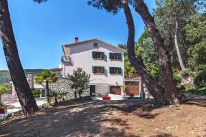 ein weißes Haus mit Bäumen davor in der Unterkunft Apartment Rabac 12 in Rabac
