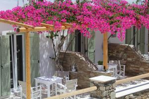 a patio with pink flowers and tables and chairs at Aegeo Inn in Antiparos