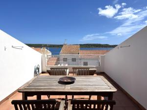 a balcony with a wooden table and chairs on a roof at Riera Rossello 1 by SOM Menorca in Fornells