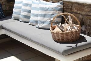 a wicker basket sitting on a bench with pillows at Aegeo Inn in Antiparos