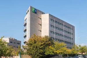 Un edificio alto con una señal verde. en Holiday Inn Express Sant Cugat by IHG, en Sant Cugat del Vallès