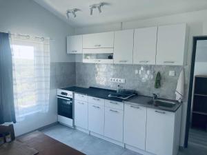 a kitchen with white cabinets and a sink and a stove at Gádé Apartmanház in Sukoró