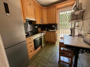 a kitchen with wooden cabinets and a stainless steel refrigerator at La Casa del Bosc, playa y golf - Salou in Salou