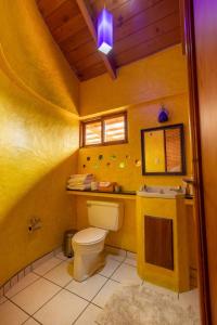 a yellow bathroom with a toilet and a sink at David's Den Atitlán in Panajachel