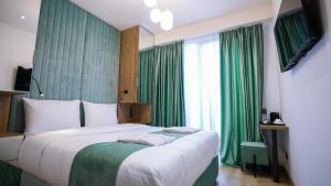 a bedroom with a large bed with green curtains at CNK Hotel By Millennium Group in Tbilisi City