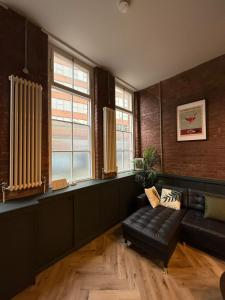 a living room with a leather couch and windows at The Hideout - Boutique 2 Bedroom Apartment in Sheffield