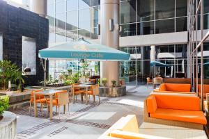 a lounge cafe with orange chairs and a blue umbrella at Ibis Al Rigga in Dubai