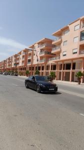 a black car parked on the side of a street at Rouge Azur Saidia in Saïdia