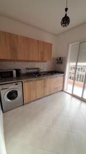 a kitchen with wooden cabinets and a washer at Rouge Azur Saidia in Saïdia +10 photos