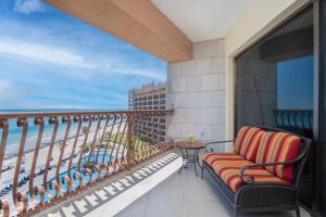 a balcony with a chair and a table and the ocean at Happy-N-The-Sun 2 BR Oceanfront in Puerto Peñasco