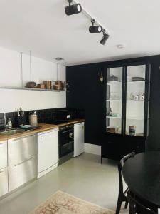 a kitchen with black walls and white cabinets and a table at Collective Yard in Braunton +26 photos