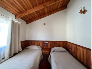 two beds in a room with wooden walls at Cabañas Parque Del Lago in Panguipulli