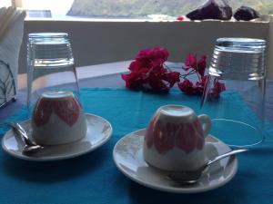 two cups on plates on a blue table with flowers at Oltremare Residence Hotel in Lipari