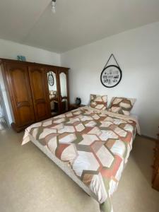 a bedroom with a large bed and a wooden cabinet at Appart Acacia Evreux in Évreux