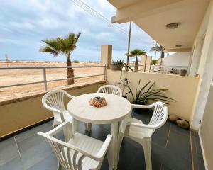a white table and chairs on a balcony with the beach at Surfing Ocean View Appartment in Sal Rei