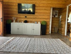 Ein Wohnzimmer mit einem Fernseher an der Wand und einem Teppich. in der Unterkunft Sub Stele Chalets in Holbav