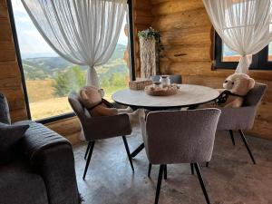 ein Wohnzimmer mit einem Tisch und einem Teddybären auf Stühlen in der Unterkunft Sub Stele Chalets in Holbav