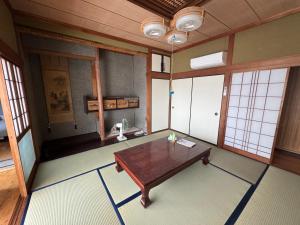 una stanza vuota con un tavolo di legno e finestre di 海と西一棟貸し宿 a Saitsuno