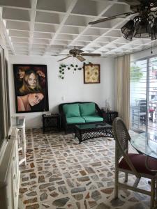 a living room with a green couch and a table at Departamento sobre Costera, 1min La Quebrada, 3m playas y yates in Acapulco