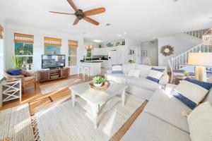 Il comprend un salon doté d'un mobilier blanc et d'un ventilateur de plafond. dans l'établissement Texas Tides, à Destin