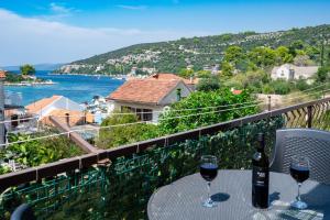 a table with two glasses of wine on a balcony at Kuća 100m od mora - Drvenik Veli in Veliki Drvenik