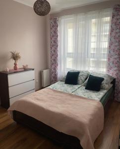 sypialnia z łóżkiem z komodą i oknem w obiekcie Apartament Miłosz w mieście Ełk