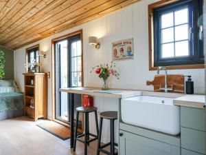 a kitchen with a sink and a counter with stools at Luxury Shepherd Hut with Private Hot Tub in Swaffham Bulbeck