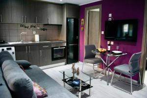a living room with a couch and a kitchen with purple walls at SkiathitissasMaison in Skiathos