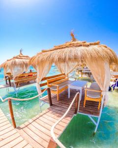 a beach with chairs and umbrellas on the water at Casa blu ghar el melh in Île Pilau