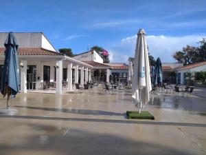 a patio with umbrellas and tables and chairs at mobil home ronce le bain in La Tremblade