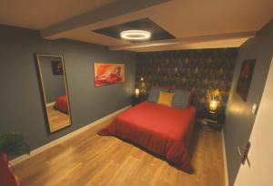 Un dormitorio con una cama roja y un espejo. en La Maison Zébulon, en Saint-Vincent-de-Paul