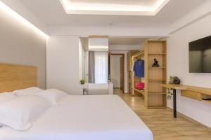 a bedroom with a white bed and a flat screen tv at Archontiko Liamas in Stavros