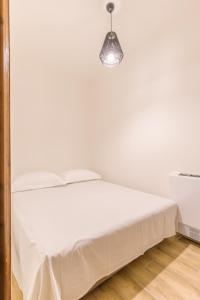 a white bedroom with a bed and a light fixture at Archontiko Liamas in Stavros