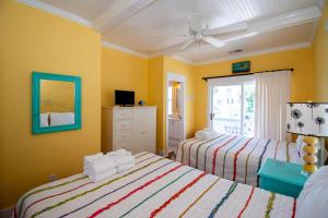a yellow room with two beds and a mirror at 46 Davis Love Cottage in Fripp Island +37 photos