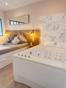 a white bathroom with a tub and a bed at Le Nid de la Chouette - Gare & Cité by Apparts Spa Dijon in Dijon