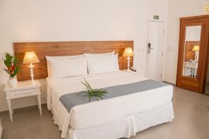 a bedroom with a large white bed and two lamps at Saint Tropez Praia Hotel in Arraial d'Ajuda