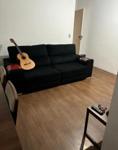 un canapé noir dans un salon avec une guitare dans l'établissement Morumbi Stadium Apartment, à Água Boa