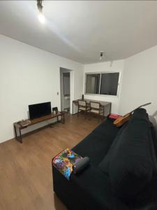 un salon avec un canapé noir et une télévision dans l'établissement Morumbi Stadium Apartment, à Água Boa