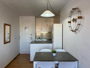 Una cocina con mesa y sillas y un refrigerador. en Costa Arenal 112 by SOM Menorca, en Arenal d'en Castell