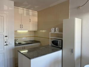 Una cocina con un refrigerador blanco y un microondas. en Costa Arenal 112 by SOM Menorca, en Arenal d'en Castell